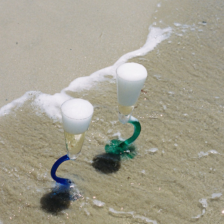 Champagne flutes with green and blue stems in the shoreline
