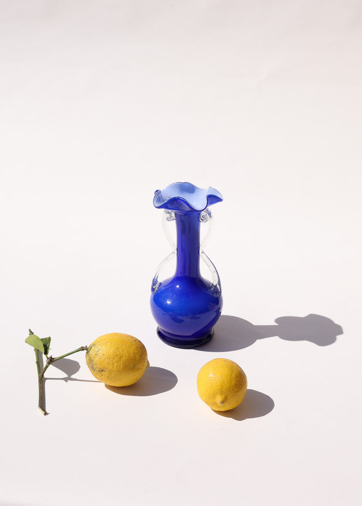 Vintage blue vase on plain background with two lemons